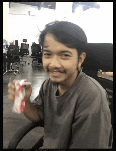 a man sitting in a chair holding a can of soda