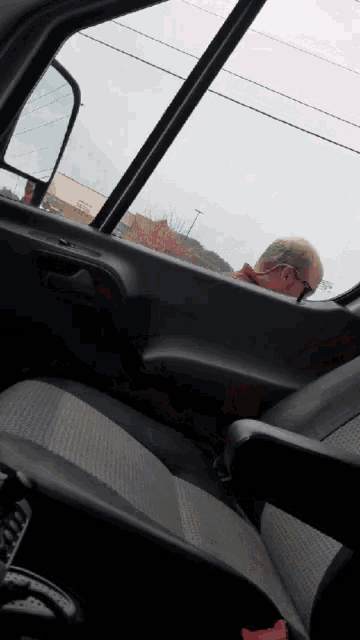 a man wearing sunglasses is looking out of a car window
