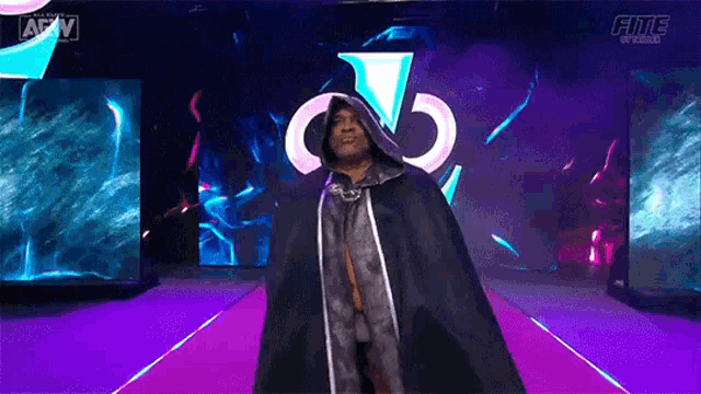 a wrestler in a cape is walking down a purple aisle .