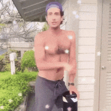 a shirtless man standing in front of a white house