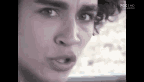 a close up of a man 's face with curly hair making a face .