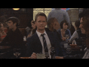 a man in a suit and tie holds up his hand in front of a sign that says ' guinness '
