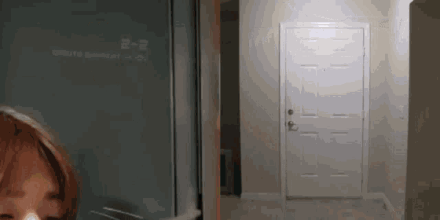 a woman is standing in front of a door with the number 2 written on it