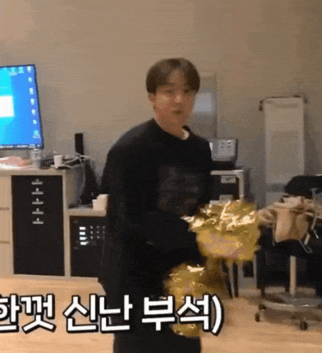 a man is holding a balloon in a room with korean writing on the wall
