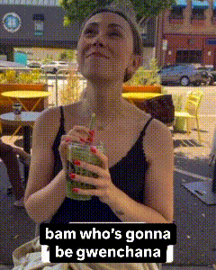 a woman in a black tank top is holding a green drink with a red straw .