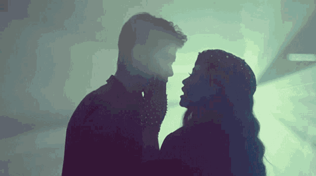 a silhouette of a man and woman kissing in a dark room