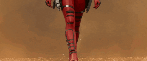 a woman in a red superhero costume holds a gun