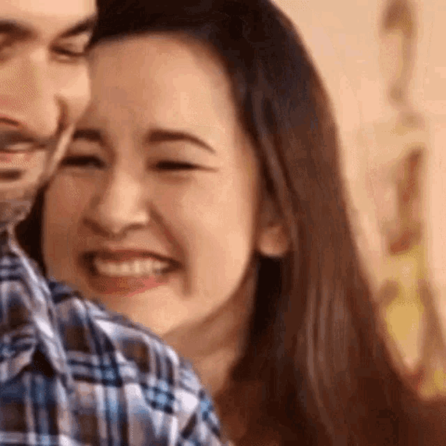 a man and a woman are smiling and hugging each other .