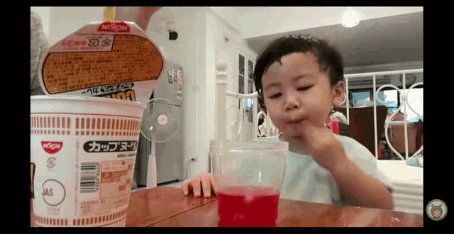 a child is drinking from a cup of nissin