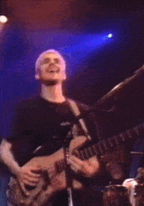 a man in a black shirt is playing a guitar in front of a microphone