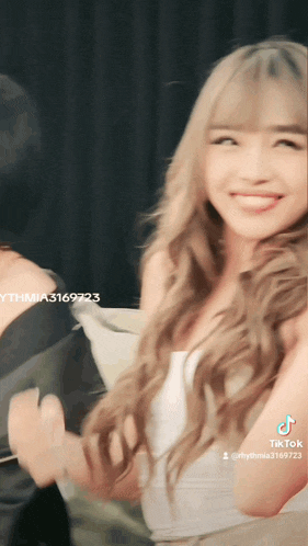 a woman with long blonde hair is smiling in a tik tok