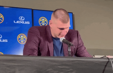 a man is sitting at a table with a microphone in front of a lexus logo