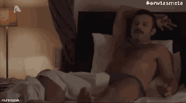 a man without a shirt is laying on a bed with the hashtag #erwtasmeta above him