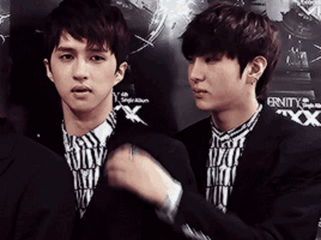two young men standing next to each other in front of a sign that says eternity