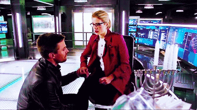 a man and a woman are holding hands in a room with a lot of monitors .
