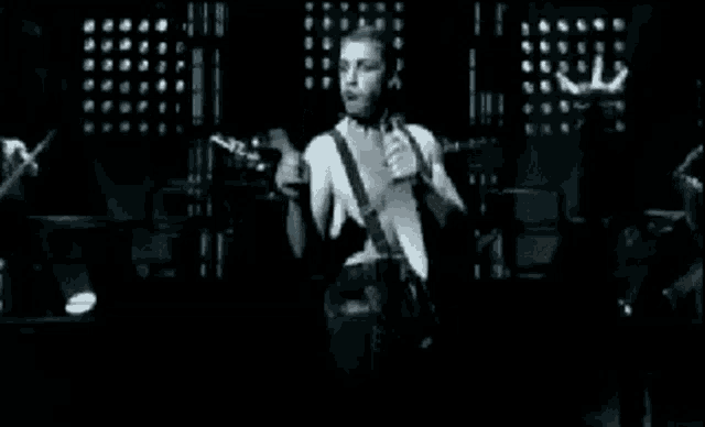 a man is playing a guitar and singing into a microphone on stage .