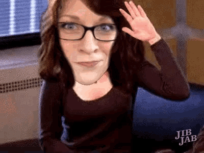 a woman wearing glasses is waving her hand in front of a window