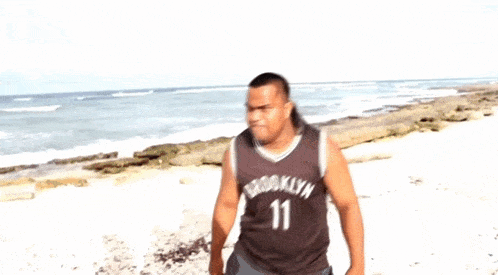 a blurry picture of two men fighting on a beach . one of the men is wearing a jersey with the number 17 on it .