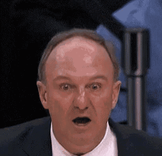 a bald man in a suit is making a surprised face .