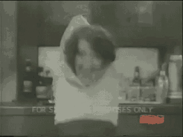 a black and white photo of a man and a woman dancing in a kitchen with the words for sale on the bottom right