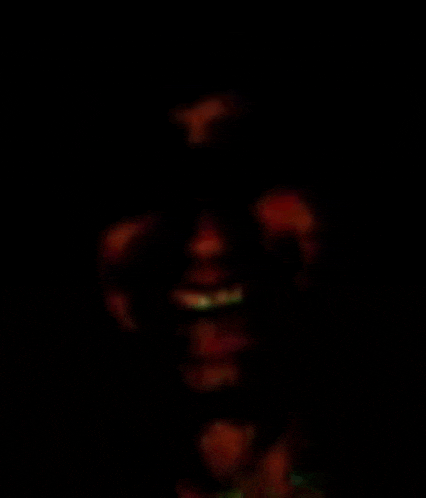 a close up of a person 's face in the dark with a blurred background .