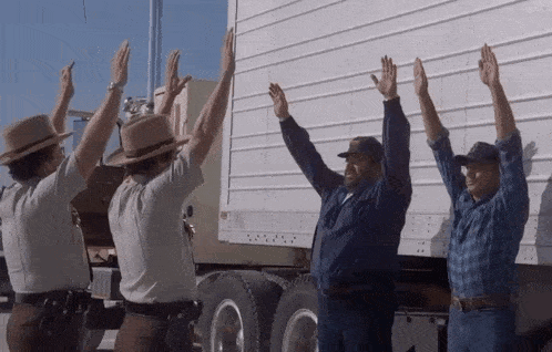 a group of men are waving their hands in front of a truck .