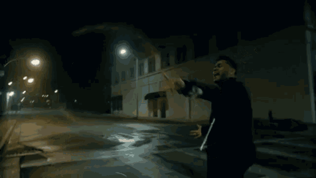 a man walking down a street at night with a sign that says one way