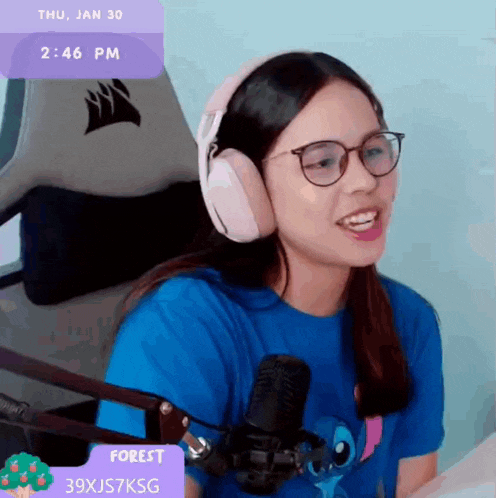 a woman wearing headphones and a blue shirt is sitting in front of a microphone with a purple box that says forest