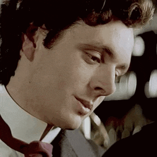 a close up of a man in a suit and tie looking at something .