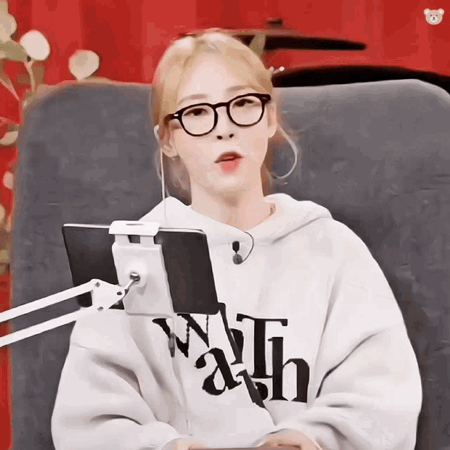 a woman wearing glasses and a sweatshirt that says faith sits in a chair