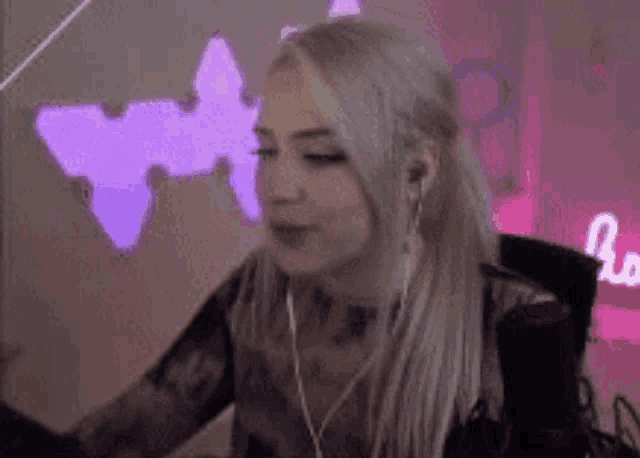 a woman is sitting in front of a microphone wearing headphones and looking at the camera .