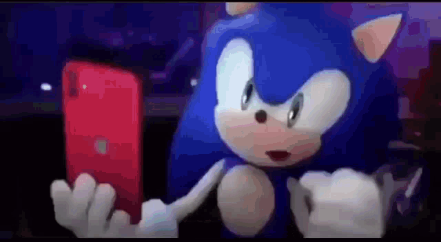 sonic the hedgehog is holding a red cell phone in his hand .