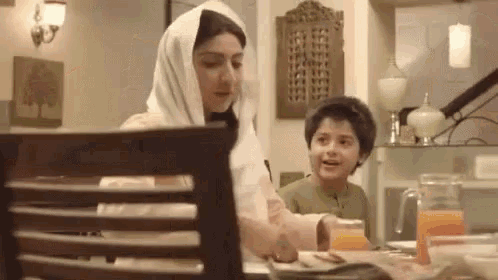 a woman and a boy are sitting at a table in a restaurant .