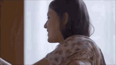 a woman is sitting in front of a window wearing a scarf .