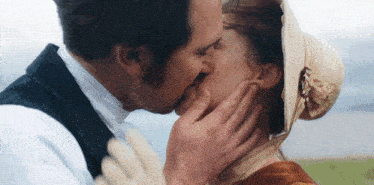 a man and a woman are kissing in front of the ocean