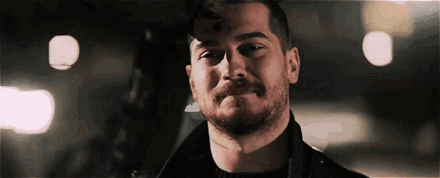 a man with a beard wearing a black jacket is smiling