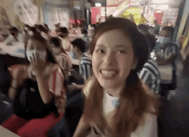 a woman wearing a mask is smiling in front of a crowd of people