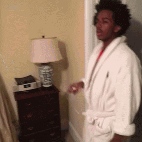 a man in a bathrobe is standing in a room next to a lamp