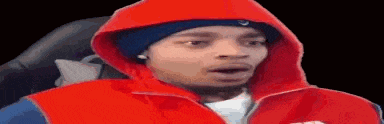 a man wearing a red hoodie and a blue hat is sitting in a chair with his mouth open .