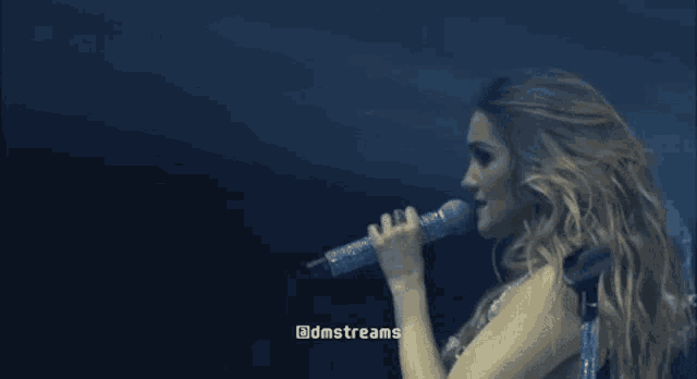 a woman is singing into a microphone on a stage with a caption that says dnstreams