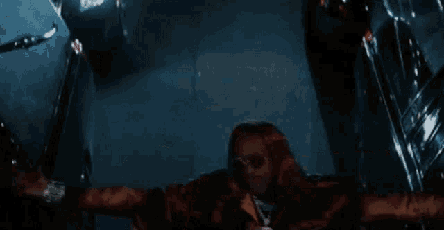 a man is standing in a dark room with his arms outstretched and looking down .