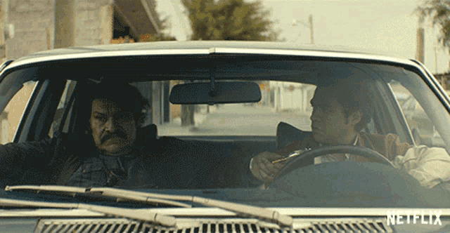 two men are driving a car with netflix written on the windshield