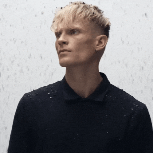 a man with blonde hair is wearing a black shirt and earrings