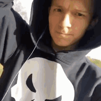 a man wearing a hoodie with a skull on it is taking a selfie .