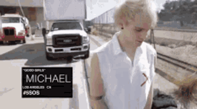 a man in a white shirt is standing in front of a truck that says michael
