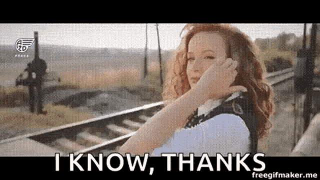 a woman is talking on a cell phone next to train tracks .