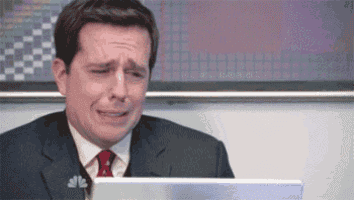 a man in a suit and tie is crying while sitting in front of a laptop .