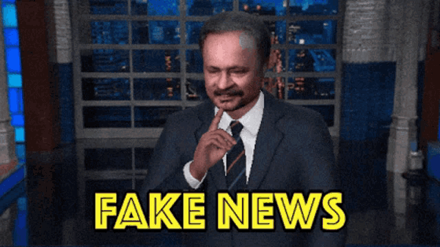 a man in a suit and tie is giving a fake news sign