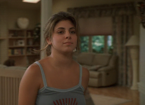 a woman in a blue tank top is standing in a hallway