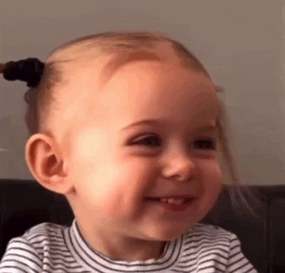 a baby girl is smiling and making a funny face .